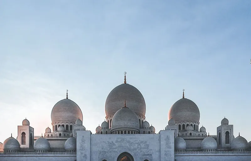 The white marble domes of the Sheikh Zayed Grand Mosque in Abu Dhabi against a blue sky
