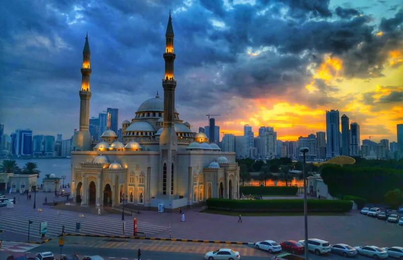 Al Noor Mosque on the Sharjah waterfront with the city skyline at sunset